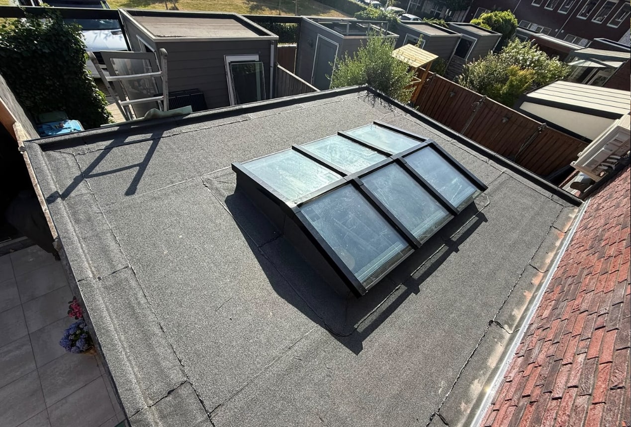 Bitumen dak van de aanbouw met lichtstraat, gezien vanaf de dakrand